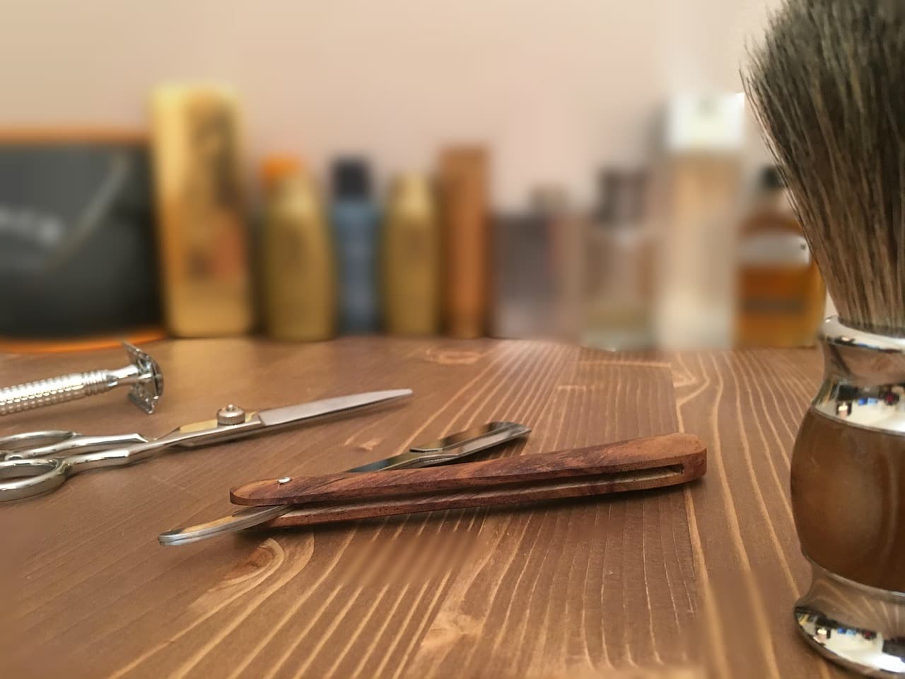A straight razor, scissors and shaving brush on a wooden counter