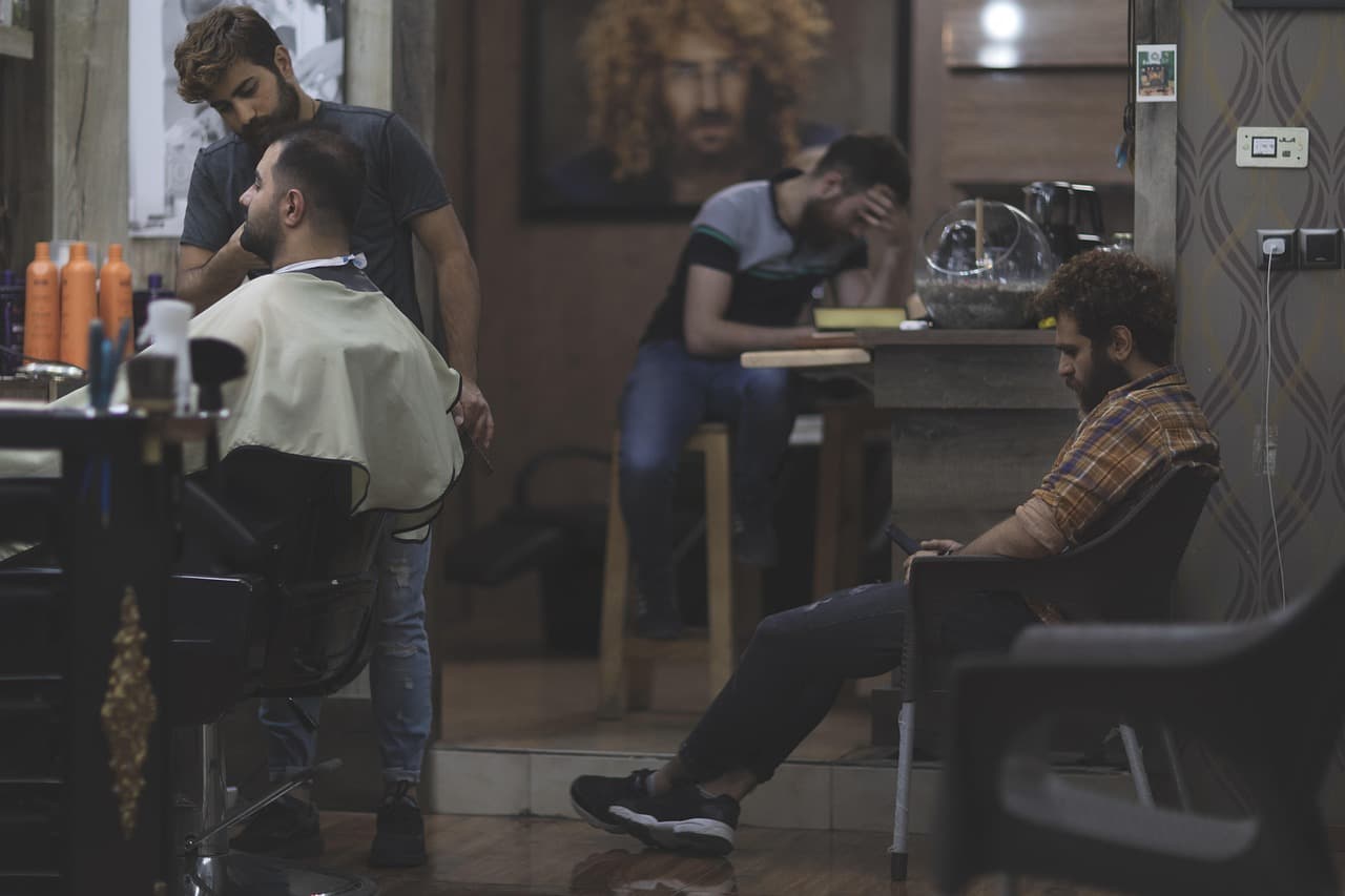 A barber at work while customers wait their turn
